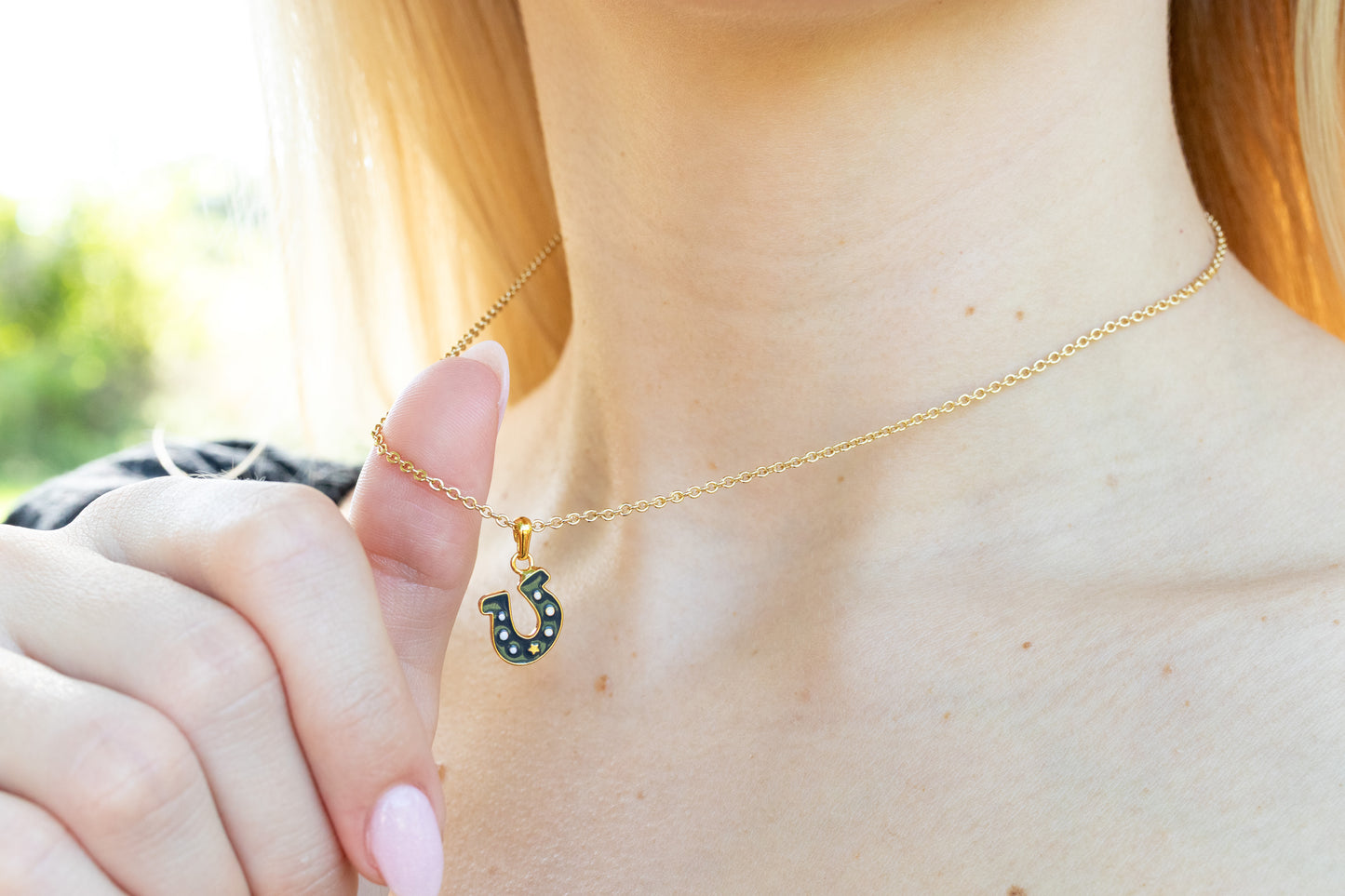 Person wearing a dark gray horseshoe necklace outdoors