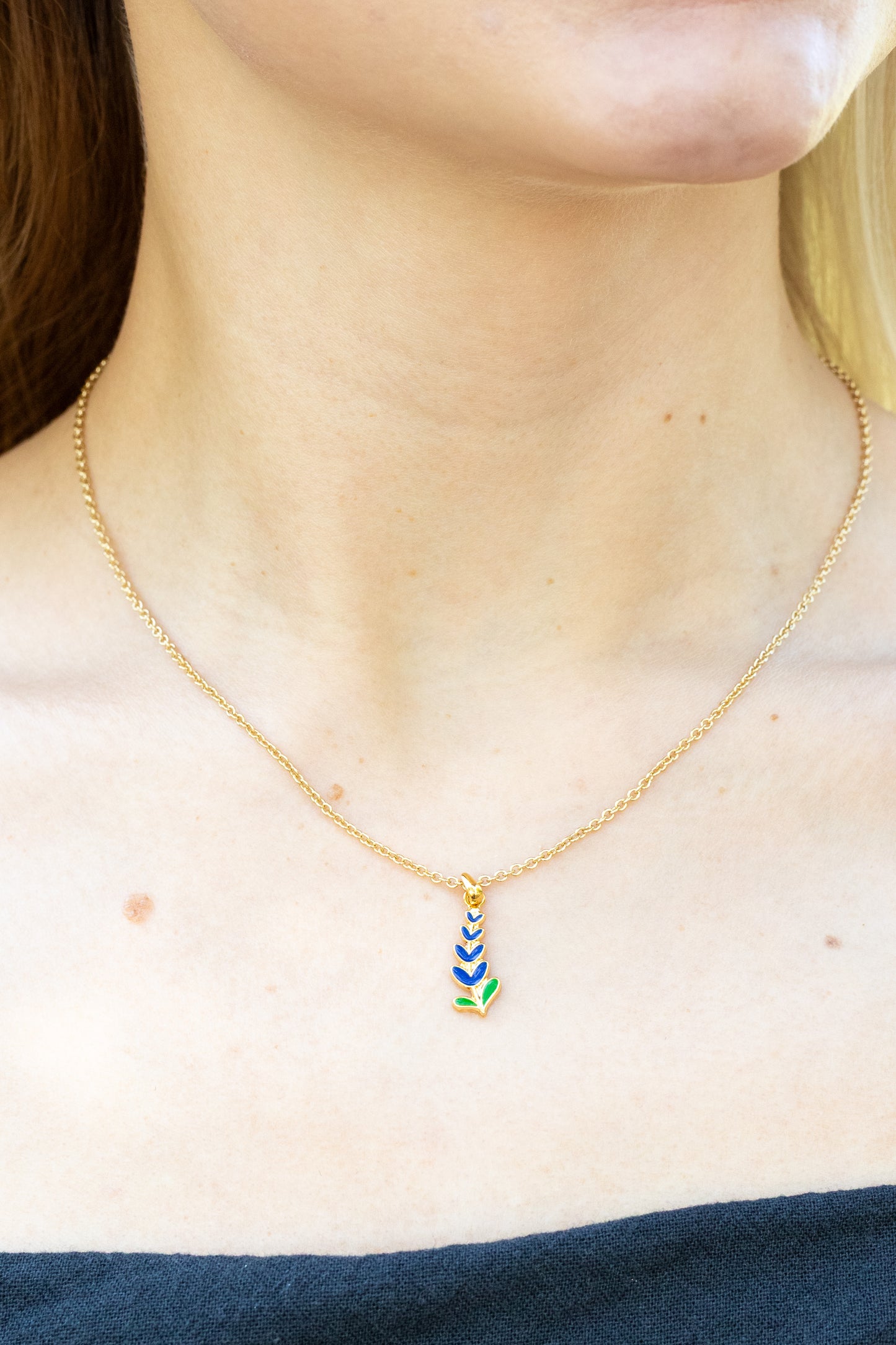 Necklace with Texas State Flower Bluebonnet on a person wearing a blue top.