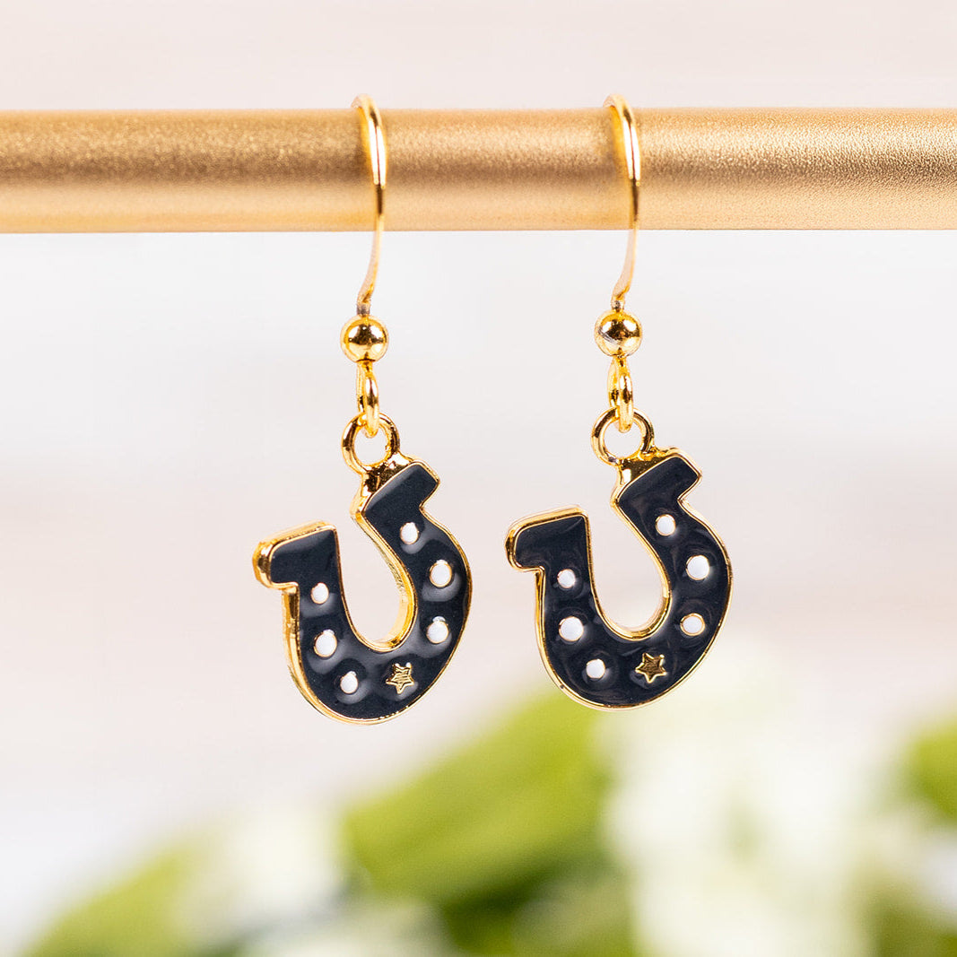 Horseshoe-shaped earrings with gold hooks on a blurred green background