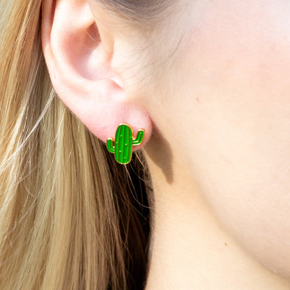 Green cactus-shaped earrings worn by a person with blonde hair.