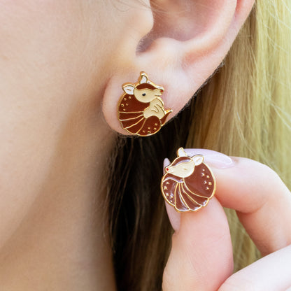 Close-up of a person wearing a brown armadillo shaped earrings.