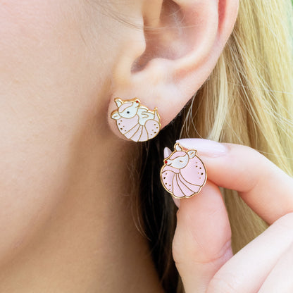 Close-up of a person wearing a pink armadillo shaped stud earrings.