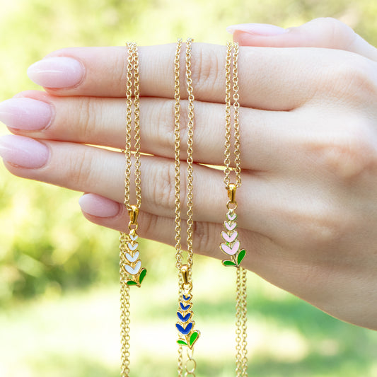 Three necklaces with Texas State flower in blue, white, and pink held by a hand against a blurred green background
