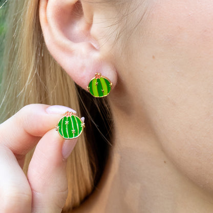 Close-up of a person wearing barrel cactus earrings with a blurred background.