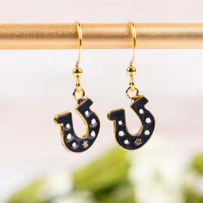 Horseshoe-shaped earrings with gold hooks on a blurred green background